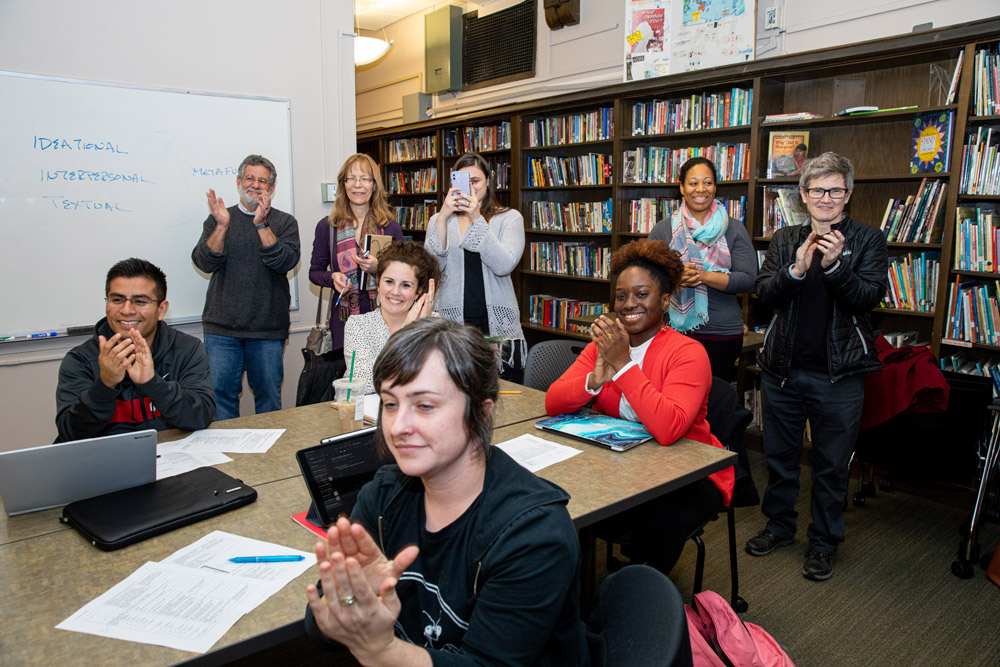 Group of men and women applaud inside university classroom