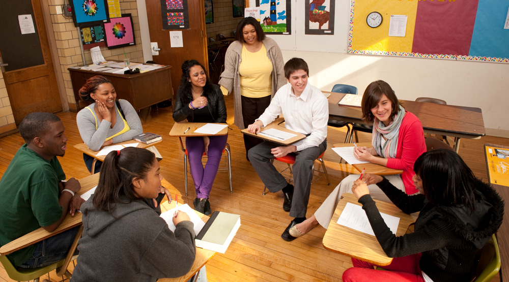 A group of students sit at desks in a circle