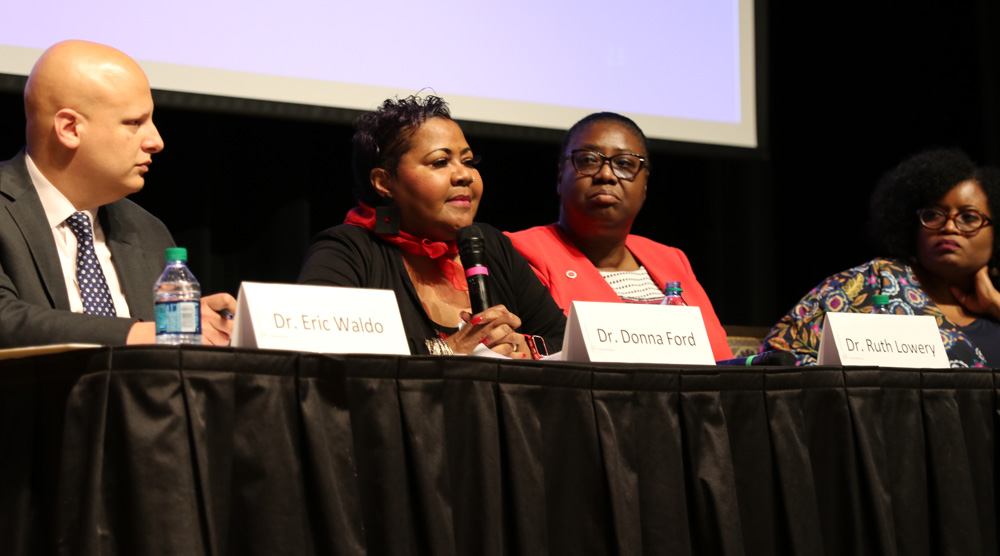 Four people sit behind a table for a panel discussion