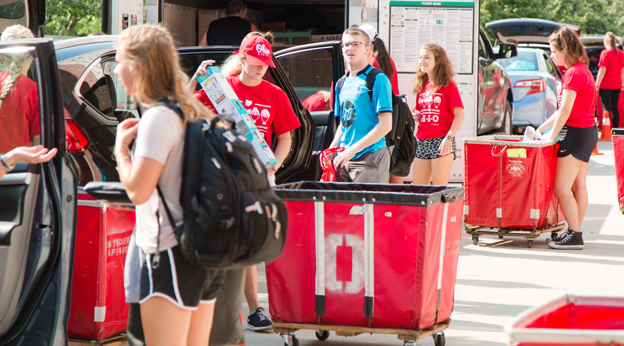 New students and Ohio State Welcome Leaders stand near vehicles loading belongings into carts on move-in day