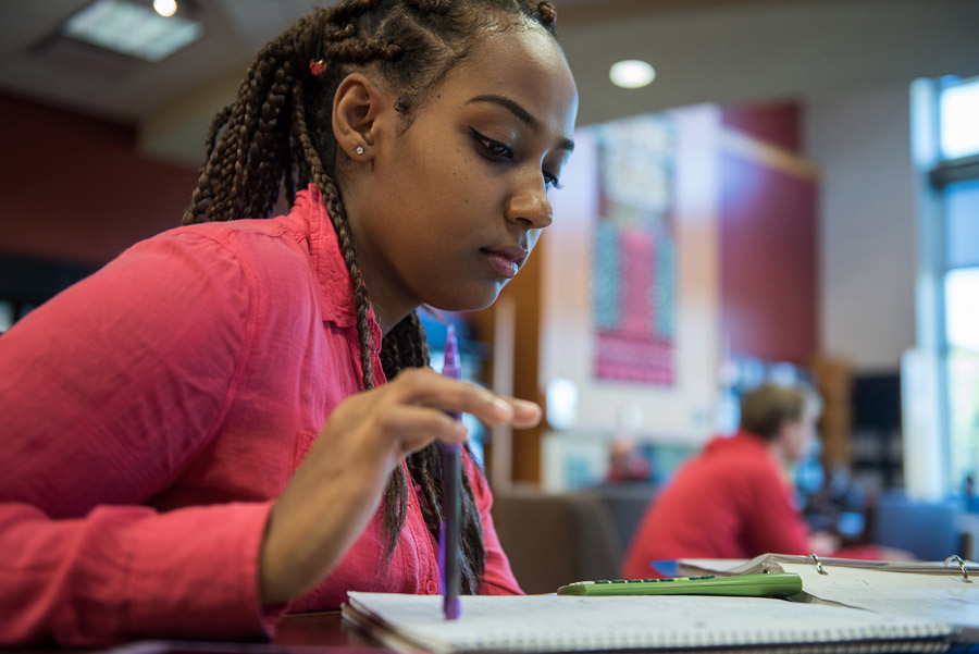 Woman holds pencil while thinking about what to write in her notebook