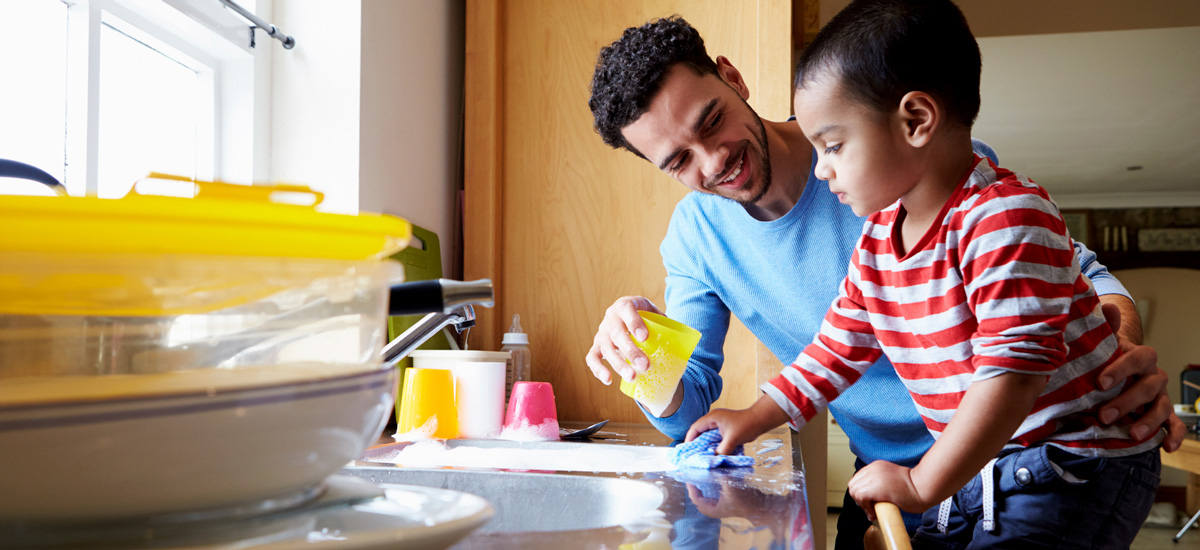 Man helps young boy wash dishes