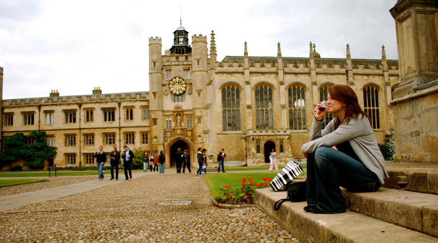 woman sits on a staircase at the University of Cambridge campus
