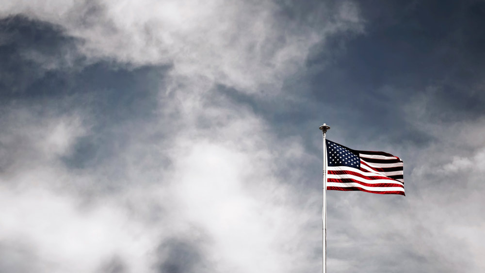 A flag of the United States of America flies against a background of wispy clouds