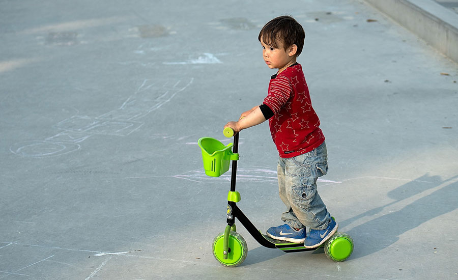 Boy standing on three-wheeled scooter