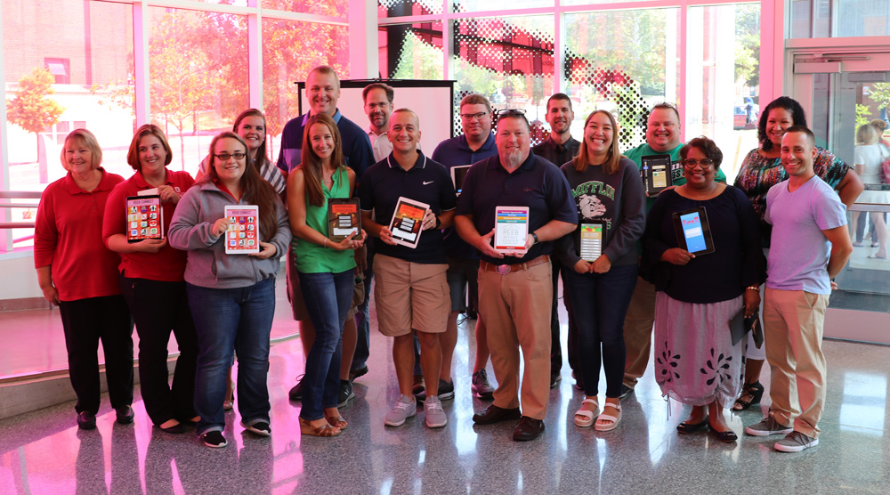 Sixteen teachers from nine schools stand together at the end of Apple's Community Education Initiative that teaches coding