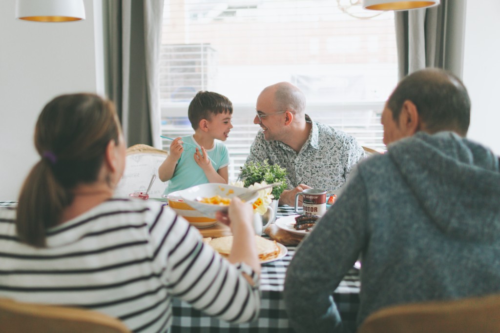 Family of four sits at table eating breakfast together