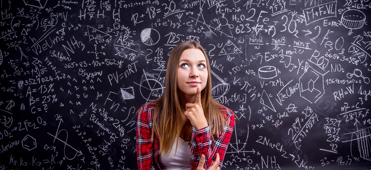 Female student seated before a blackboard with math equations written on it