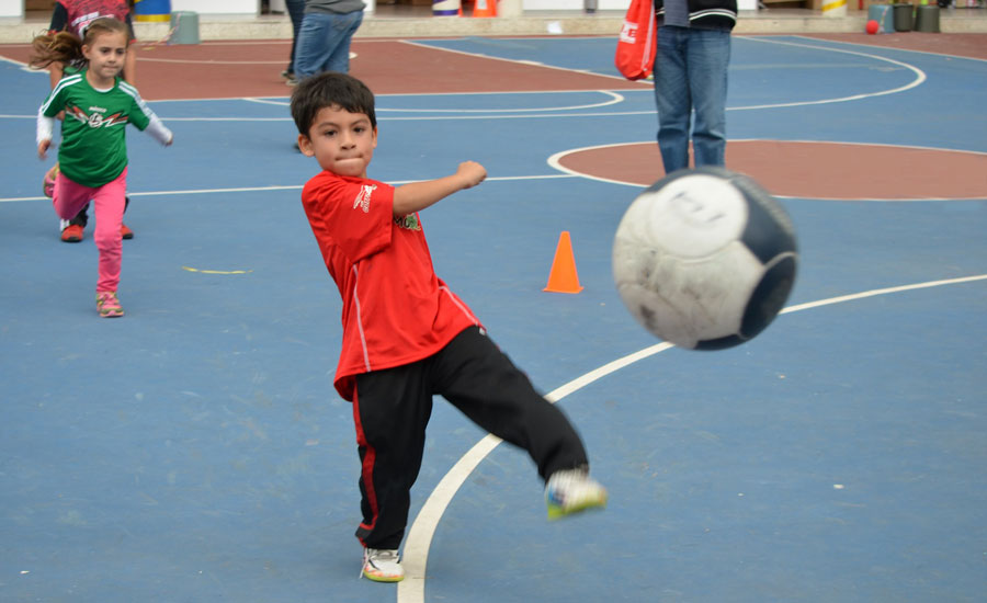 Boy kicking soccer ball on basketball court