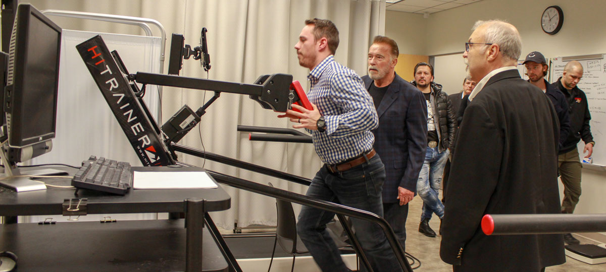 Post-doctoral student demonstrates sprint treadmill for Arnold Schwarzenegger