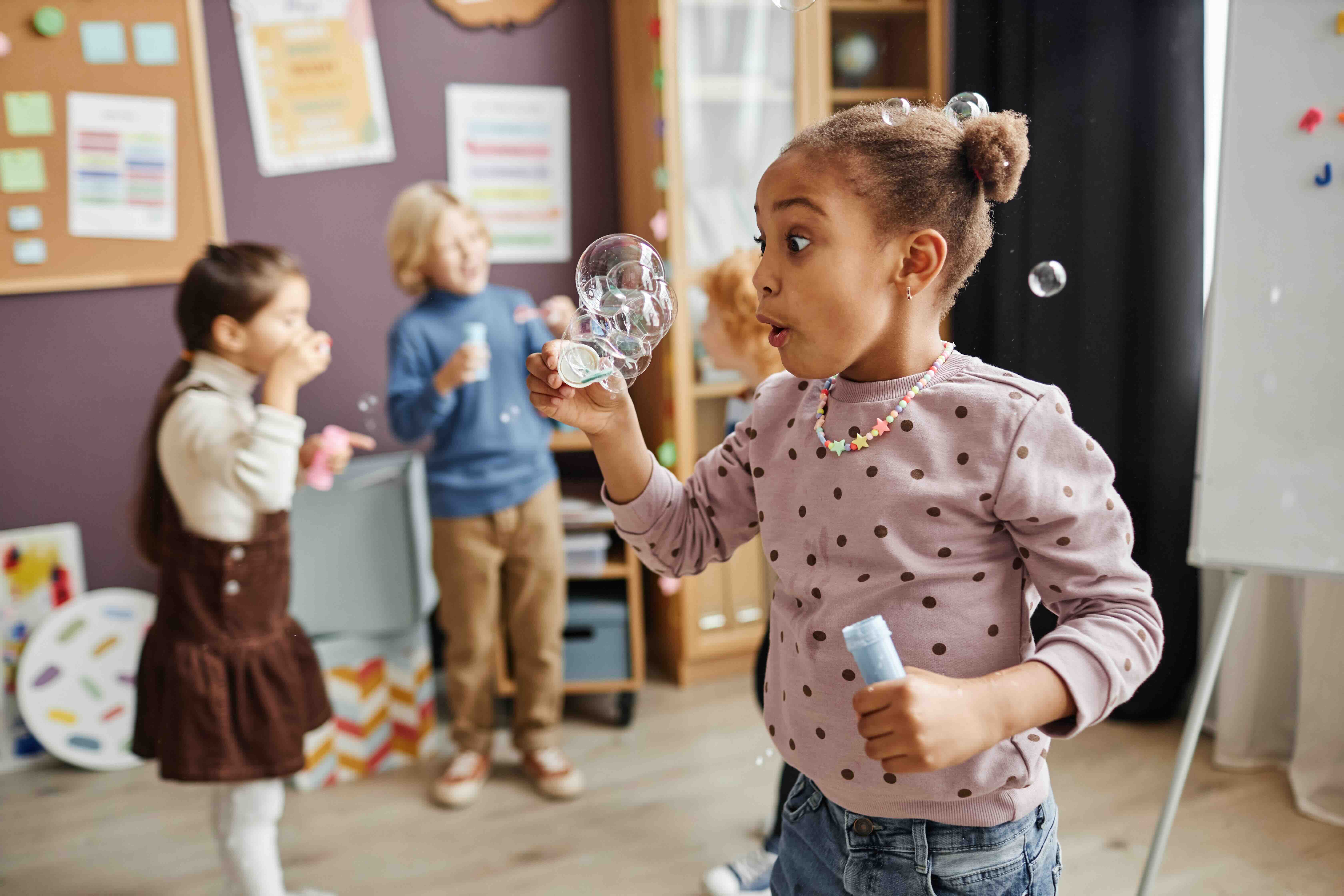 kindergarten student blowing bubbles in a classroom
