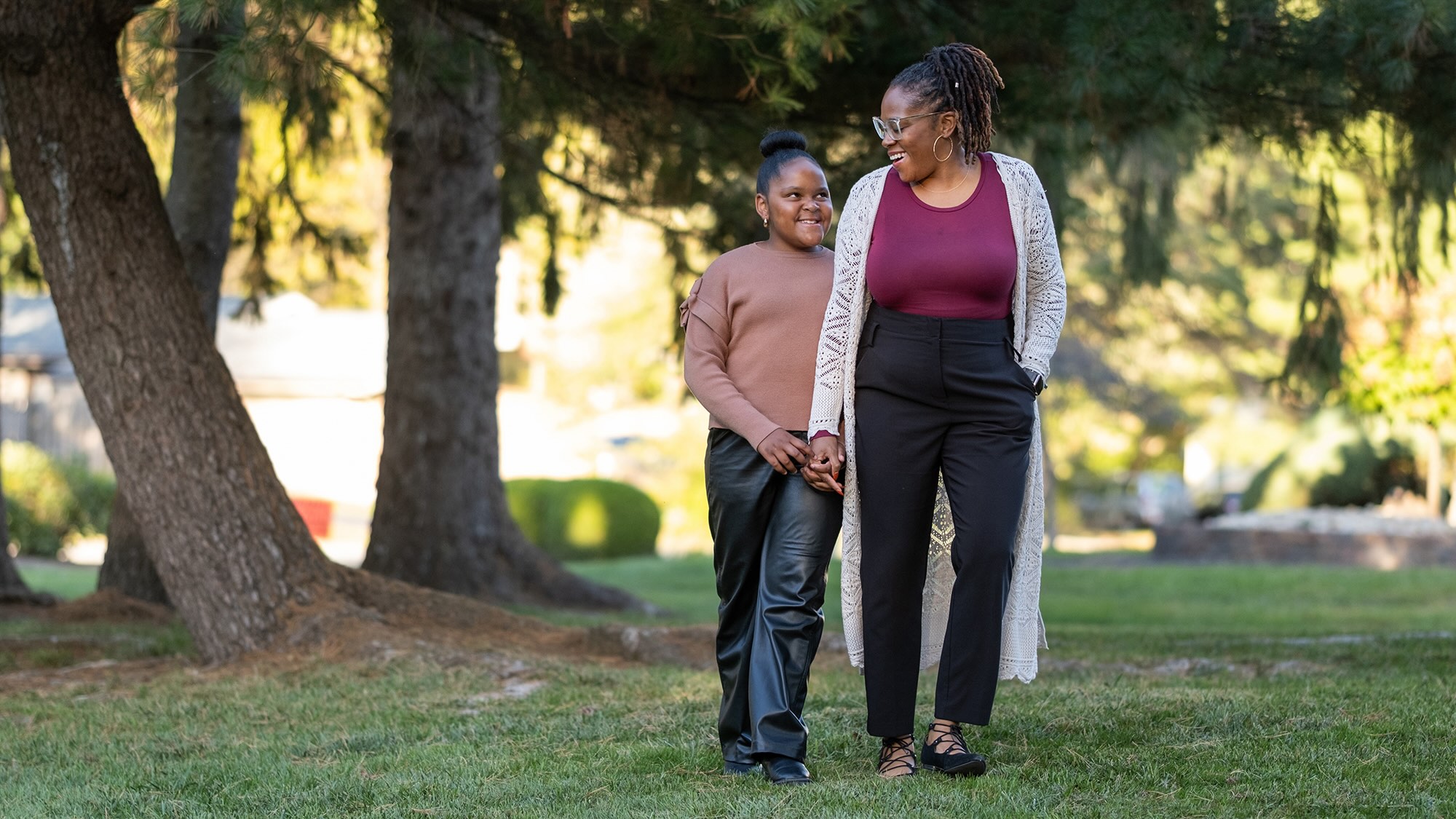 Mother and daughter walking through their yard holding hands
