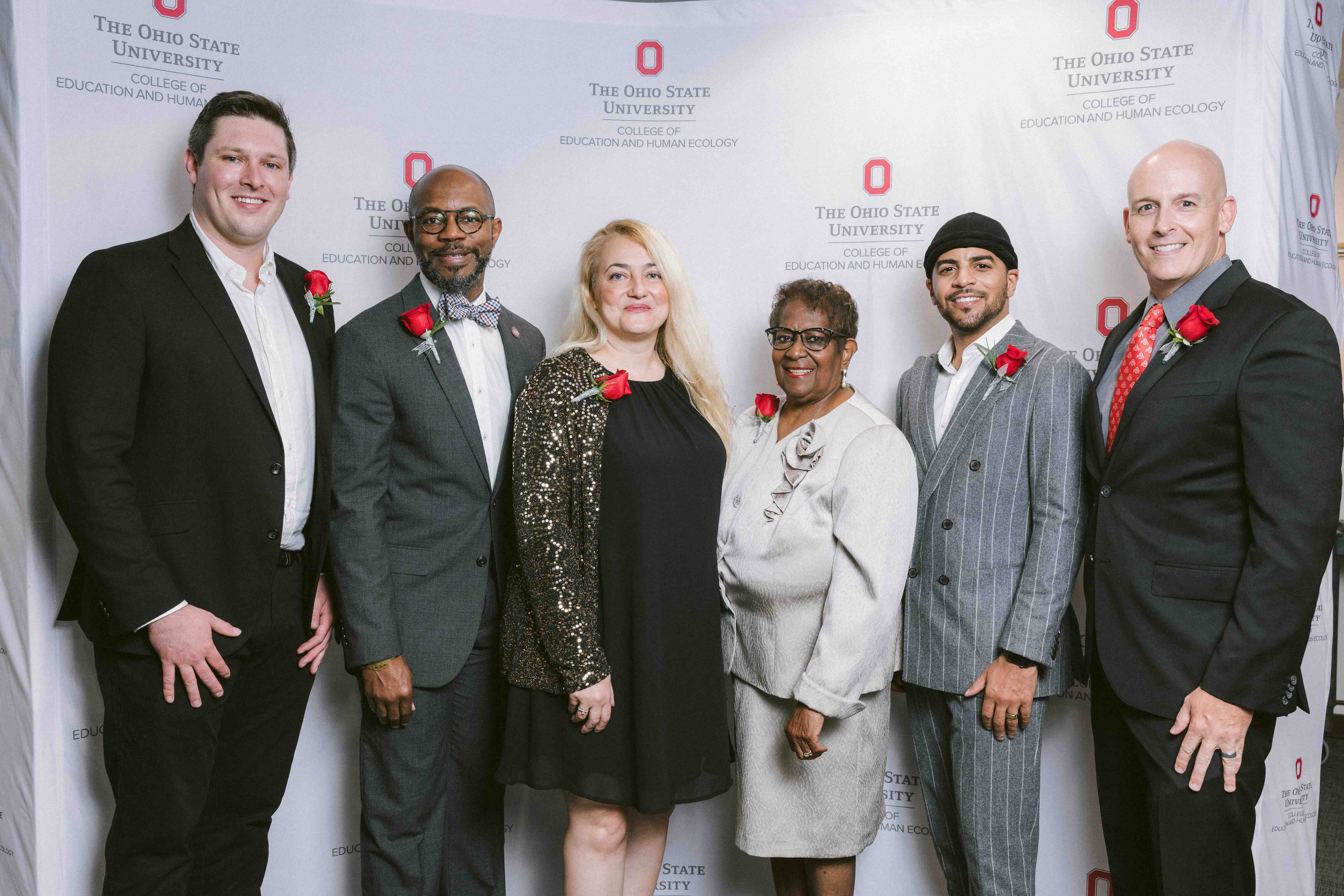 Ohio State alumni posing in front of backdrop at a homecoming event