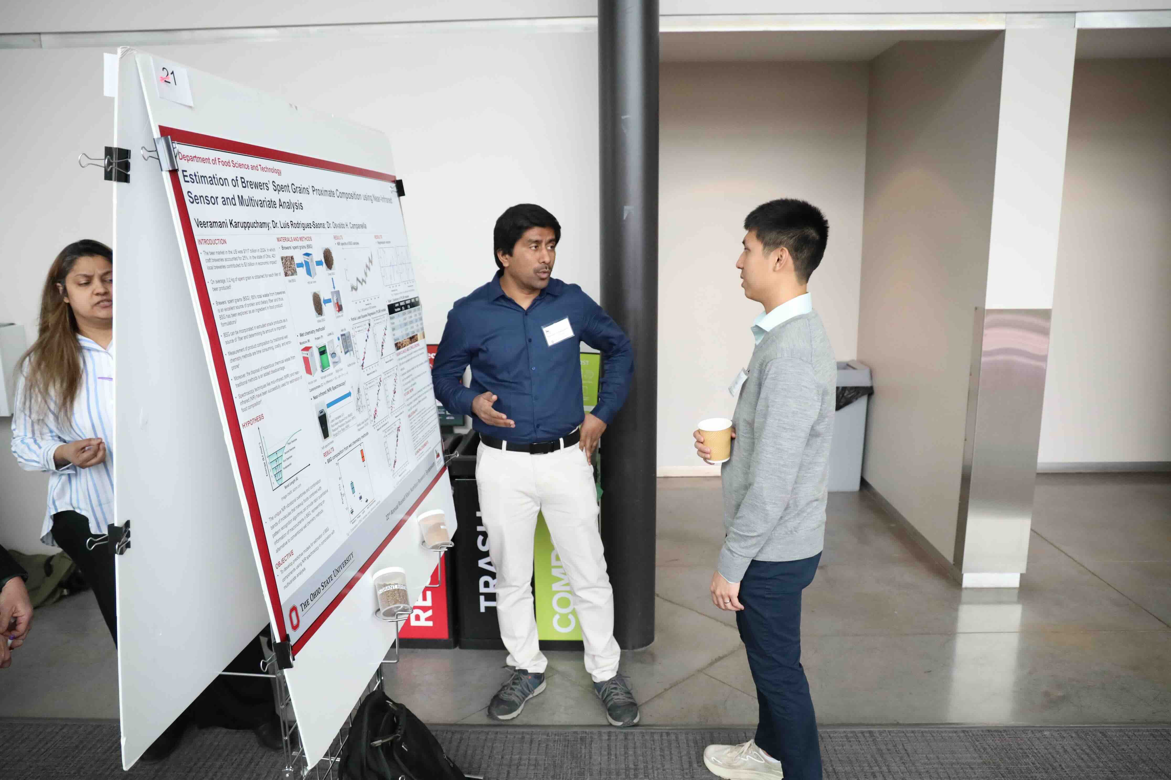 A research student discussing his poster board presentation at a symposium
