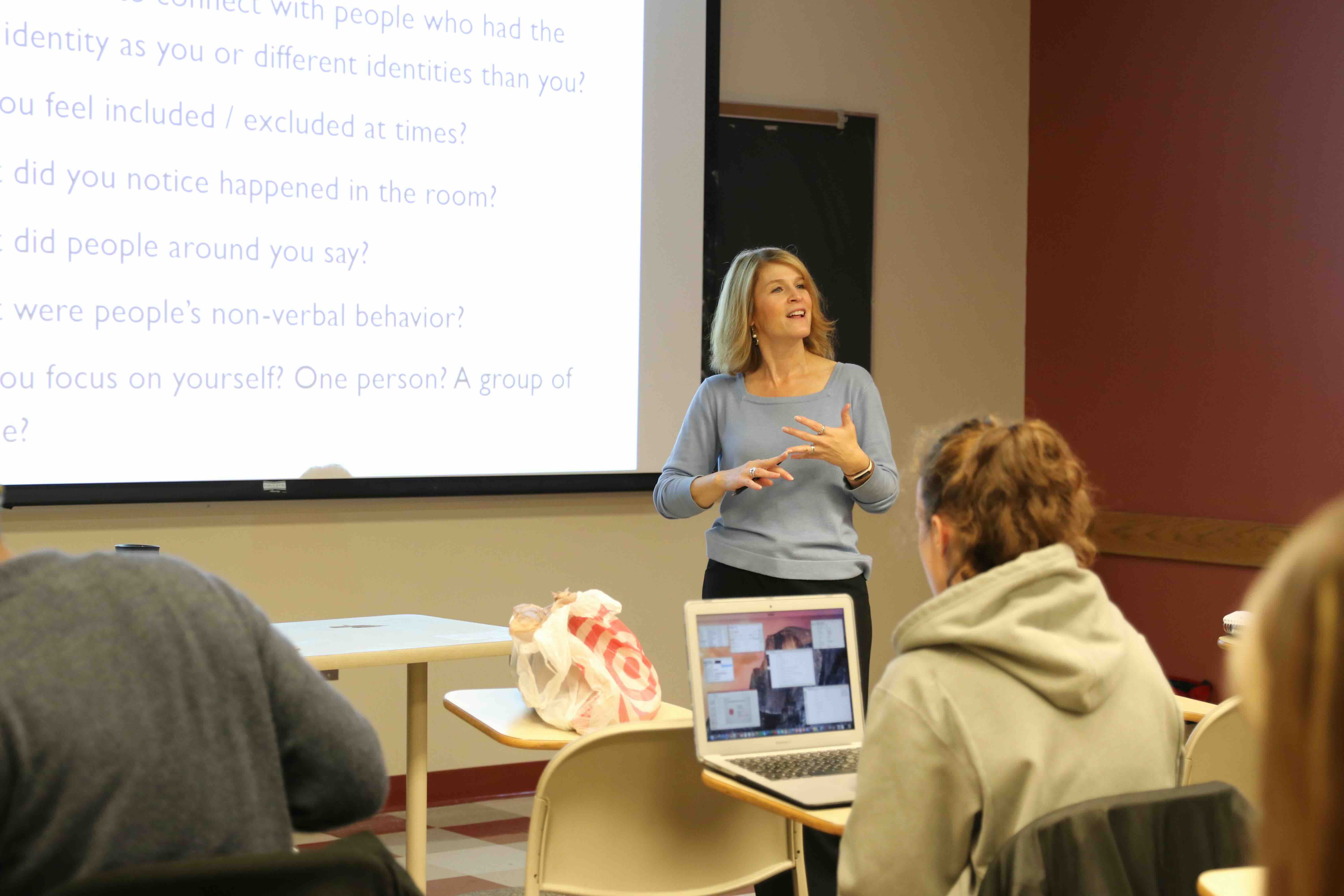 Penny Pasque at the front of a college lecture speaking to a room of students
