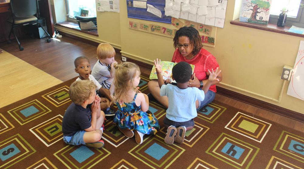 Woman reads book to group of preschoolers