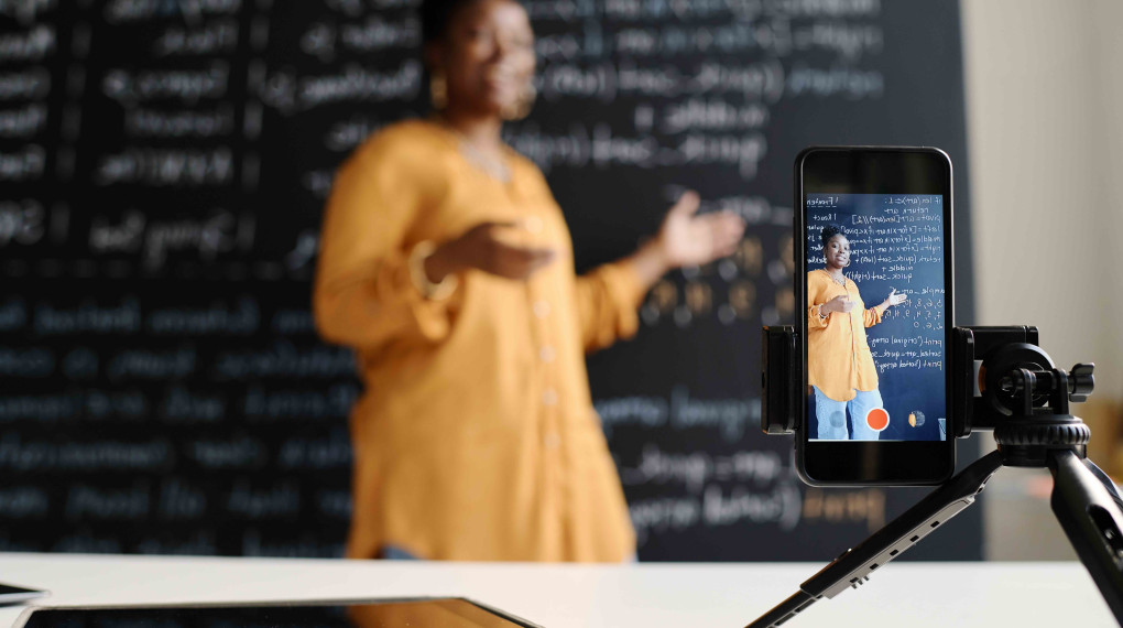 Woman teaching in front of a blackboard while being recorded