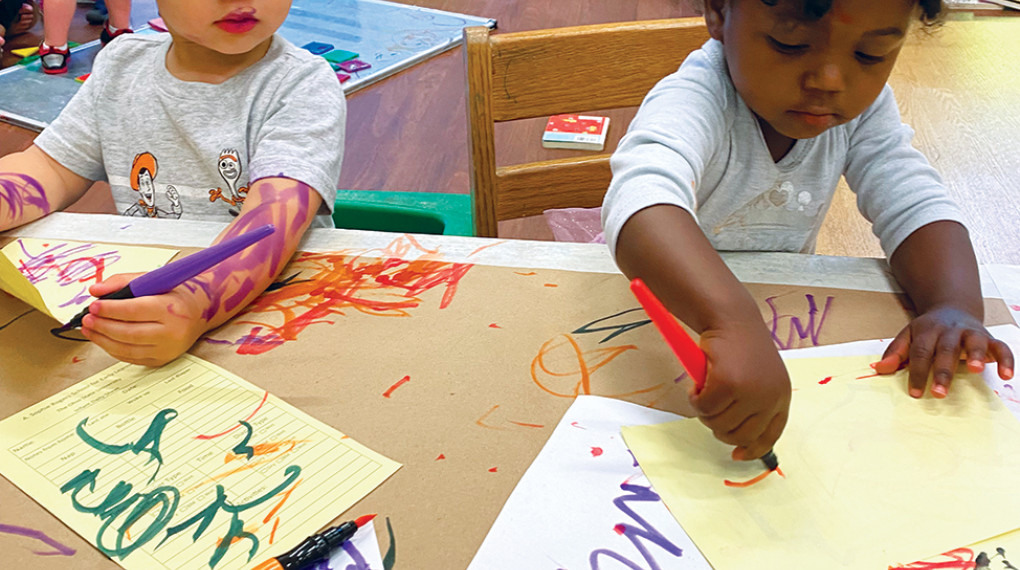 two young children coloring in school