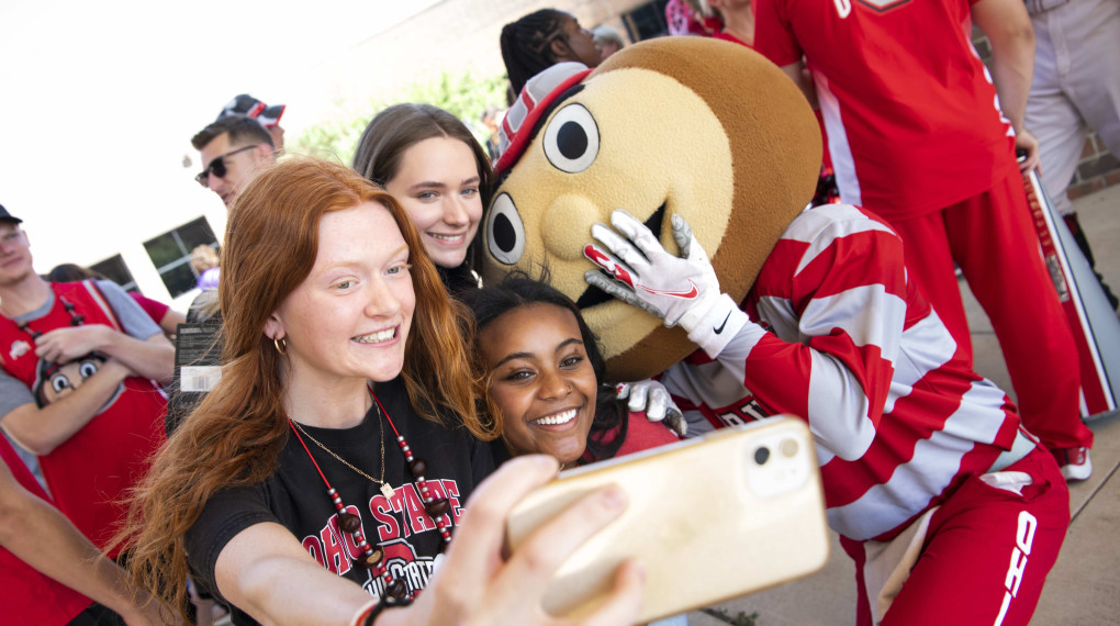 First year Ohio State students with Brutus the Buckeye at a tailgate taking a selfie.