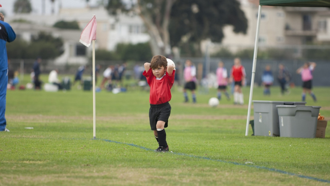 small child playing soccer on a field