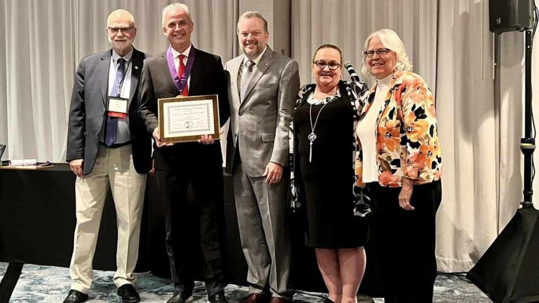 Ohio State faculty Brian Turner holding a plaque posing with a group of other Kinesiology members.