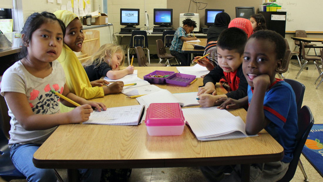 School children sitting at shared table doing a workbook