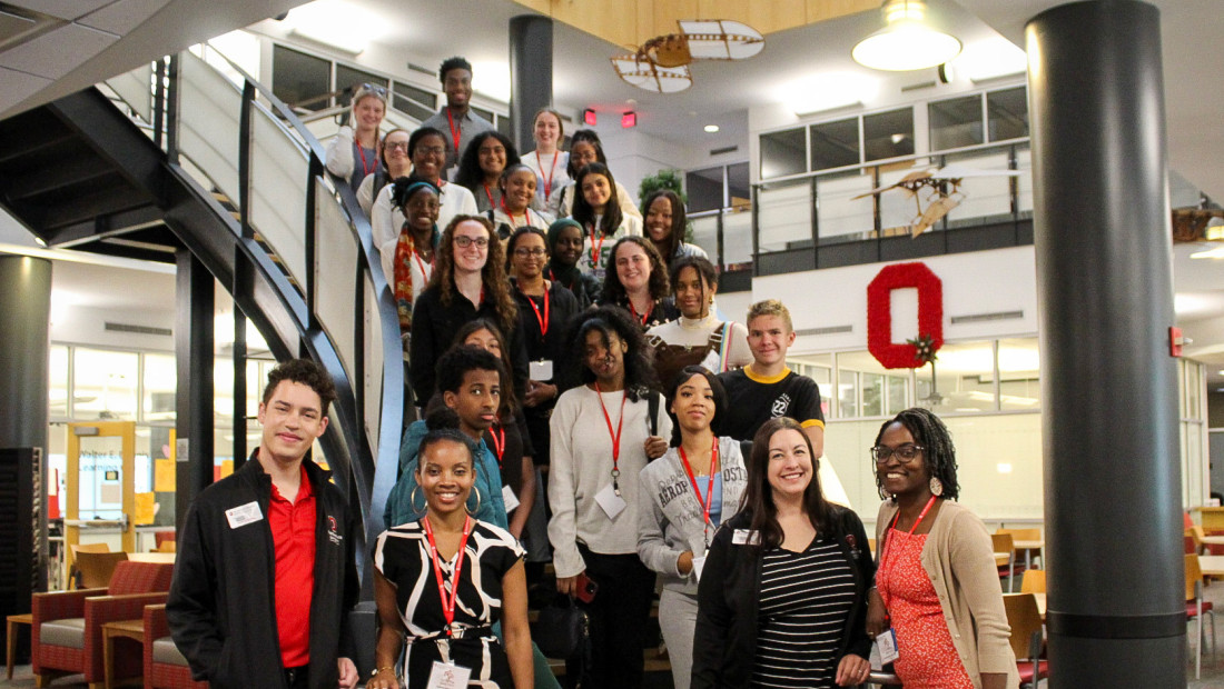 A group of students stand on stairs smiling at the camera