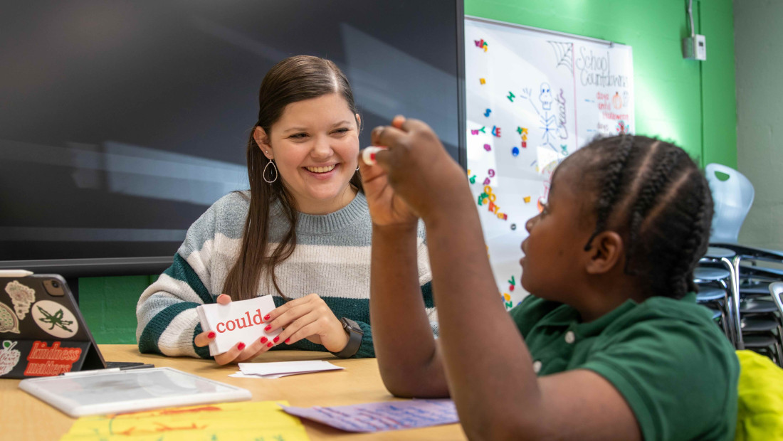 Female teacher working with a young student on reading skills