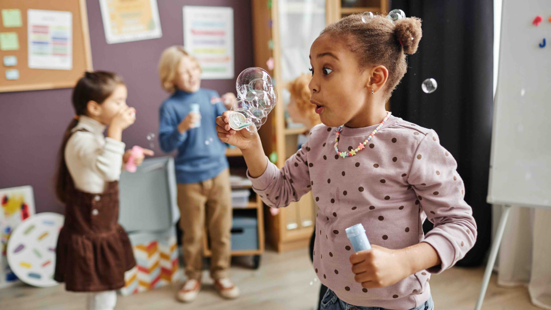 kindergarten student blowing bubbles in a classroom