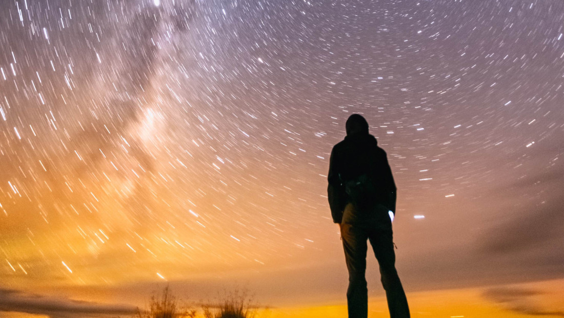 hiker silhouetted against the starry night sky 