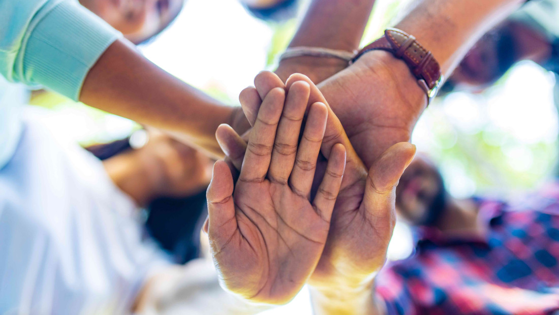 large group of diverse people with their hands out in front together