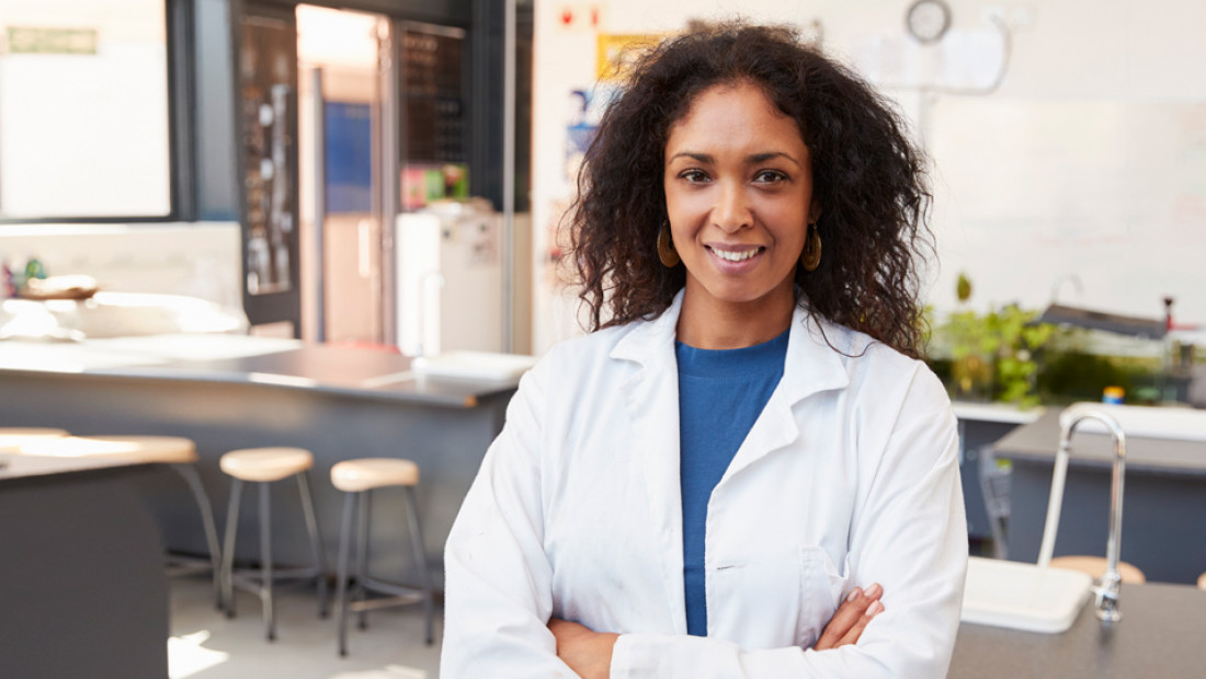 female science teacher in lab coat smiling in school
