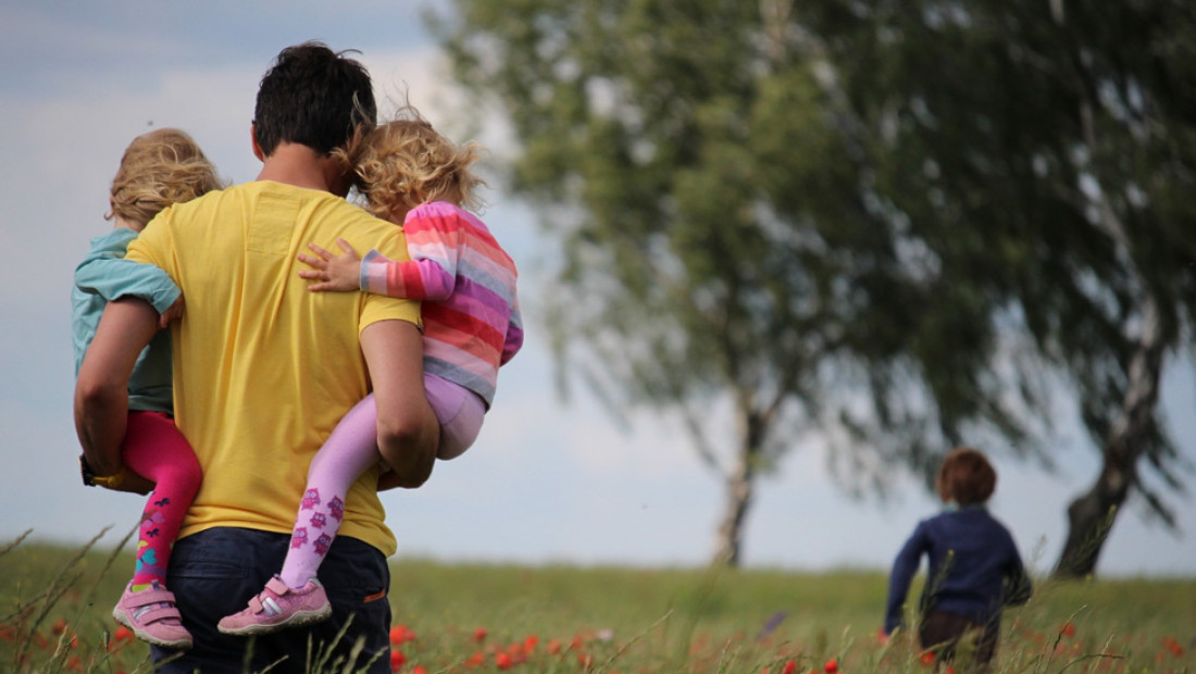 man carrying two small children