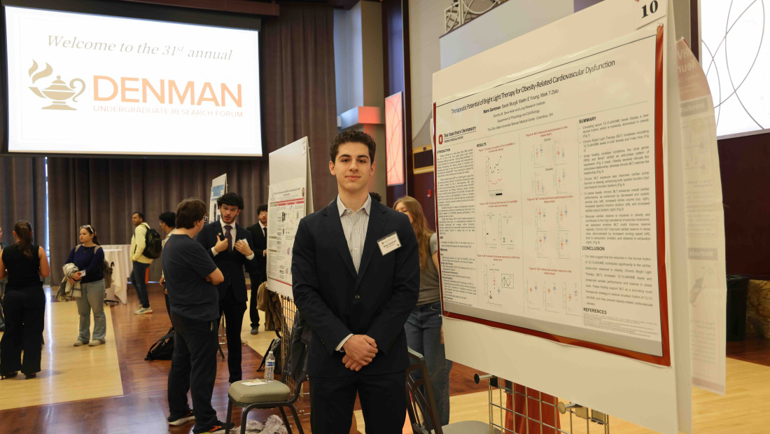 Student standing next to poster presentation at a research forum