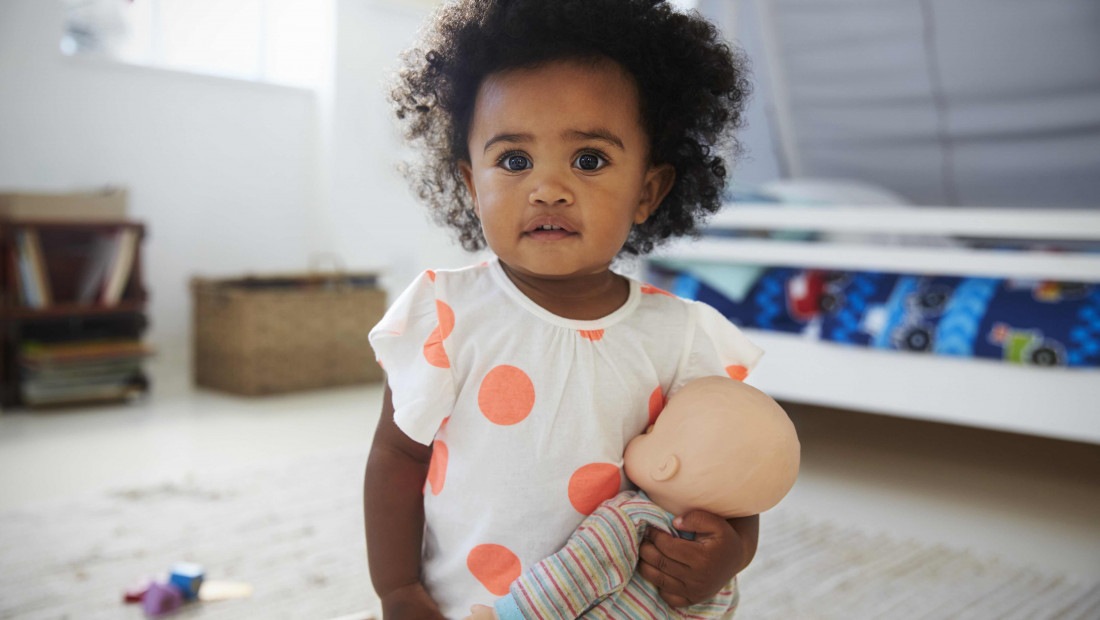 child in playroom holding baby doll