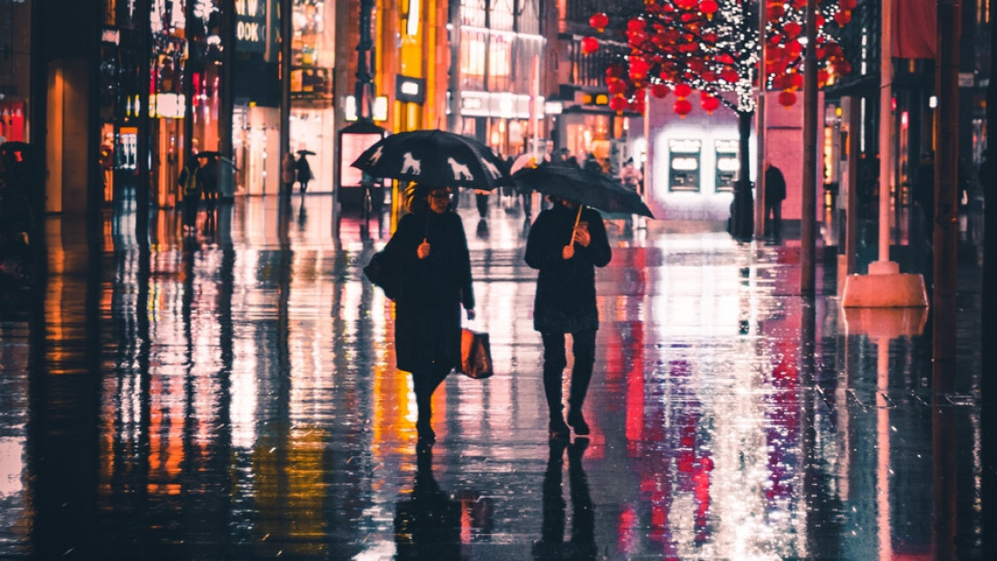 a couple of people walking down a street holding umbrellas