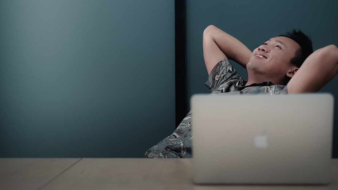 person smiling behind laptop