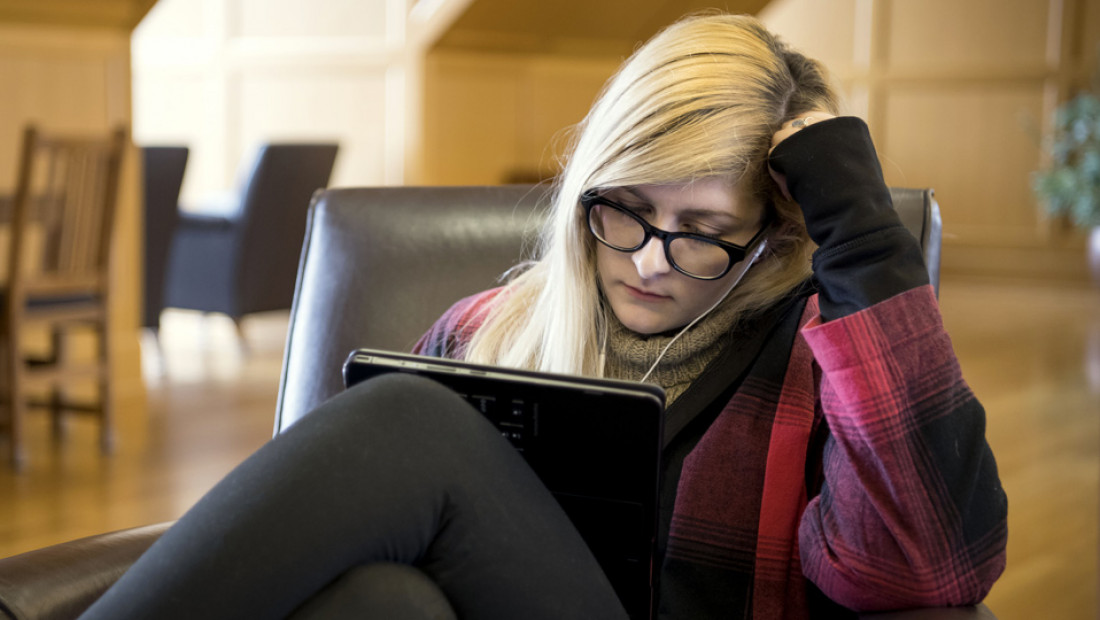 a woman sitting in a chair looking at a laptop