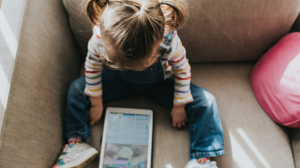 Young child sitting on couch looking at an iPad