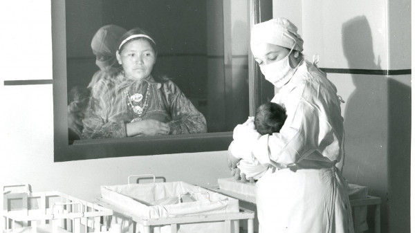 Native American mother looking through hospital window at her child