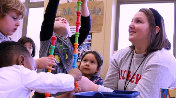 Teacher with young students playing with construction toys