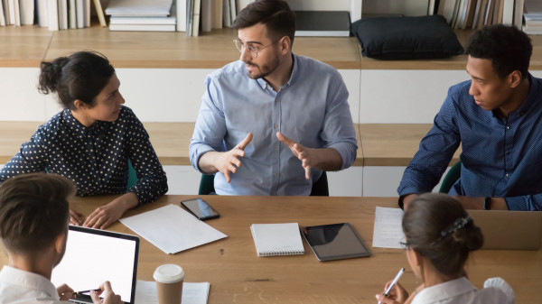 Skilled male manager talking to diverse business people at meeting