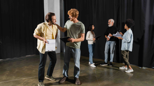 actors and directors on a stage reviewing scriptd