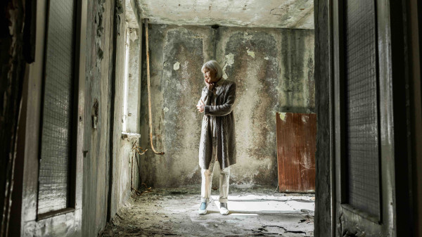 Older woman standing in a lonely building looking sad
