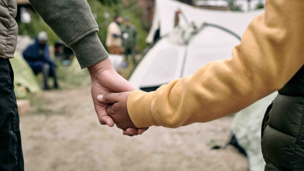 Mother and child holding hands in front of campsite