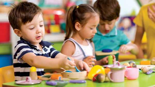 children with toy kitchen in classroom