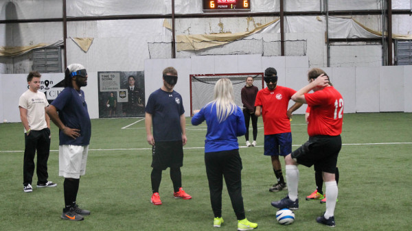 visually impaired soccer players listening to coach