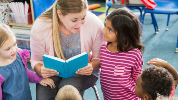 a teacher reading a book to children in a classroom