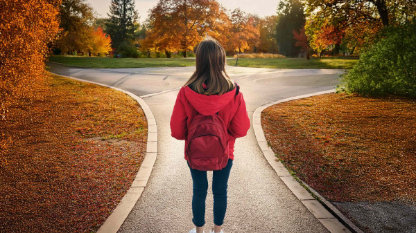 student wearing a backpack looking out onto a fall day on the Oval