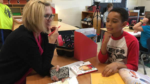 a teacher sitting at a table with a child